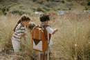 Children exploring a grassy field with a backpack
